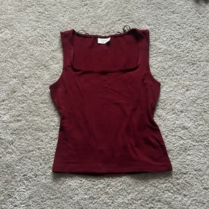 Vinröd linnetopp från Gina Tricot - Snygg vinröd linnetopp från Gina Tricot. Perfekt för en stilren look med sin enkla design och fyrkantiga halsringning. Tillverkad i mjukt material för en bekväm passform.