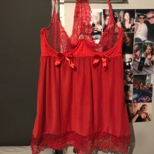 Röd spets klänning  - Säljer en röd spets klänning med spetsdetaljer och rosett framtill. Linnet har tunna axelband och en vacker spetskant längst ner. Den är köpt begagnad så inte den bästa kvaliteten på spetsen men resten av klänningen är de inget fel på.(Natt klänning /lingerie)