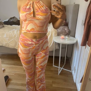 Färgglad set - Säljer en färgglad sett  med mönster i rosa, orange och vitt. Toppen har en öppen rygg och är croppad med ett snyggt snitt framtill. Perfekt för sommarens varma dagar! Endast använd 2 gånger,