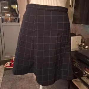 Svart rutig kjol från American Apparel - Snygg svart kjol med rutigt mönster från American Apparel. Kjolen har en dragkedja på sidan för enkel på- och avtagning. Perfekt för en stilren look.