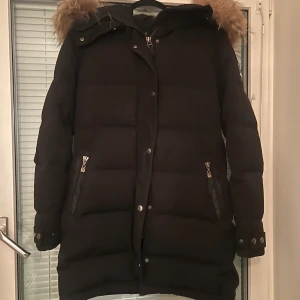 Hollies jacka men äkta päls  - Hollies subway dunjacka i storlek 42.  En bra och varm jacka, som jag har använt kanske två vintrar den är i helt okej skick men har små fläckar som man kan se på dom sista bilderna. Pälsen är jättefin, och går att ta av om man vill. Ordinarie pris är 4295.