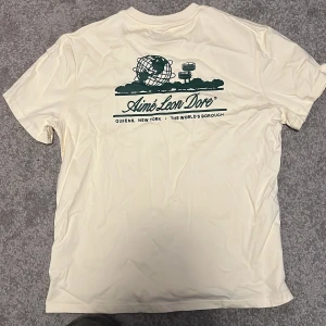 Vit t-shirt från Aimé Leon Dore - Snygg vit grön Aime Leon Dore t-shirt köpt i new york på en streetwear outlet. Säljer då den inte passar längre. Storlek S men sitter mer som M. Tveka inte att skriva! Pruta ska nog gå