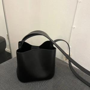 Svart axelväska med dragkedja - Säljer denna väska från Gina tricot. Nästintill oanvänd och därför i nyskick. Finns ett fack med dragkedja inuti. Kontakta vid funderingar😊