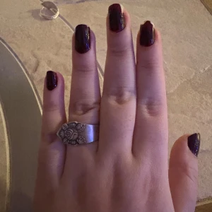 Silverfärgat ring med rosdetalj - Unikt silverfärgat ring med vacker rosdetalj på framsidan. Perfekt för att ge en elegant touch till din stil. Ring har en slät yta och en robust design. 