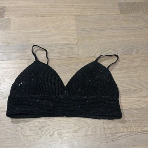 Svart paljettprydd topp från NLY Trend - Snygg svart topp från NLY Trend med glittrande paljetter. Den har smala axelband och en ribbad detalj under bysten. Perfekt för en festlig kväll!