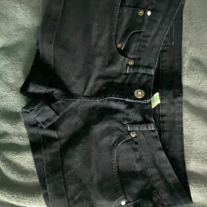 Lågmidjade shorts - Snygga svarta shorts med nitar på bakfickorna. Perfekta för en cool och avslappnad stil. De har en klassisk femficksdesign och knappar i metall. De har även en väldigt låg midja.