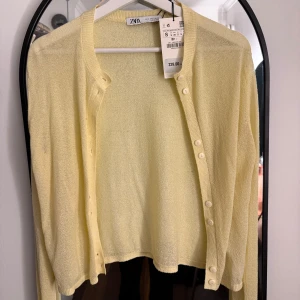 Gul kofta från Zara - Säljer en ljusgul kofta från Zara i storlek S. Koftan har långa ärmar och knappar framtill. Perfekt för vår och sommar!