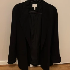 Nästan nytt! Svart kavaj från H&M - storlek L - Dags att rensa min garderob. Använde den ba 1-2 gånger. Fortfarande hel och inga trasig.   75 cm längd från axeln till nedåt  44 cm från axel till axel  60 cm från axel till arm. Kavajen har tre fusk fickor. Vet ej om det går att ta bort snöre så att fickor skulle öppna. 