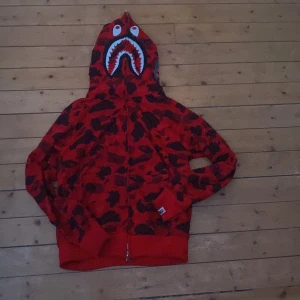 Röd babe hoodie  - Säljer en röd camo hoodie från A Bathing Ape . Hoodien har den klassiska designen. Den är galet skön och ser fett bra ut. !Panda buy!