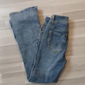 Blå jeans med bootcut - Snygga blå jeans med bootcut-stil och dubbla knappar i midjan. Aldrig använda. Från NVFelix nypris runt 290kr säljer för 220kr.  Midjemått 63cm. Innerbensmått 75cm.  Strlk Xs 32