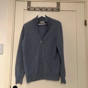 Blå kashmirtröja från Soft Goat - Säljer en stilren ljusblå kashmirtröja från Soft Goat med dragkedja framtill. Tröjan har långa ärmar och en klassisk passform, perfekt för kyligare dagar. Mjuk och bekväm att bära. Väldigt bra skick 9,5/10. Nypris - 2895kr 😱 Mitt pris: 1699kr 💯Kan gå ner i pris vid snabb affär! Skriv om du har någon fråga eller liknande! (Dåligt ljus på bilderna)