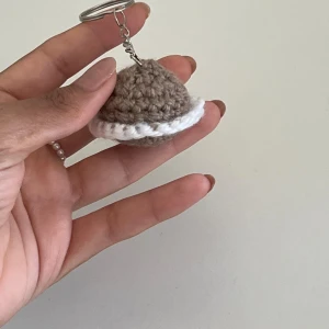 Handgjorda virkade nyckelringar - Unika virkade nyckelringar i olika former och färger. En brun och vit hatt, röda körsbär med gröna blad, en rosa rosett och en rosa blomma med mörkare mitt. Perfekta som personliga accessoarer eller presenter.
