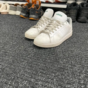 Vita Adidas sneakers - Säljer ett par klassiska vita Adidas sneakers med gröna detaljer. Skorna har snörning och en stilren design som passar till många olika stilar. Dom är i storlek 43 och är otroligt sköna att gå i men säljer dom nu för har köpt ett par nya då dom gamla inte passade min stil 