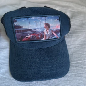 Grå stickad mössa och blå keps med motiv - Säljer en grå mössa ifrån Revenite och en Monaco keps av Revenite har aldrig använt mössan  