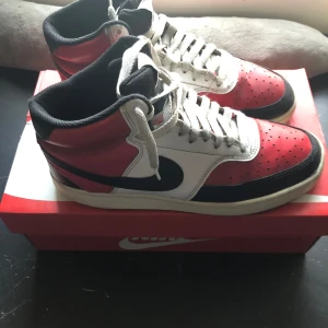 Nike Air Jordans i rött, svart och vitt - Säljer ett par klassiska Nike Air Jordans i rött, svart och vitt. Skorna har en hög modell med snörning och den ikoniska Nike-loggan på sidan. Perfekta för sneakerheads som älskar retrostil. Pris kan diskuteras 
