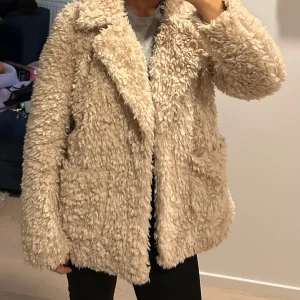 Beige teddyjacka - Mysig beige teddyjacka med lång ärm och klassisk krage. Perfekt för kyliga dagar när du vill hålla dig varm och stilren. 