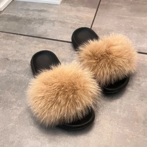 Svarta sandaler med beige pälsdetalj - Snygga svarta sandaler med en fluffig beige pälsdetalj på ovansidan. Kan användas både utomhus eller inomhus. Stl 38/39