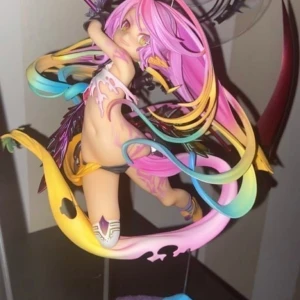 Färgglad animefigur - En detaljrik animefigur med långt, färgglatt hår i rosa, gult och blått. Figuren har en dynamisk pose och bär en fantasifull dräkt med vingar och dekorativa element. Perfekt för samlare av animefigurer.