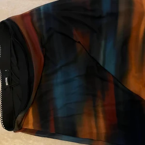 Flerfärgad kjol från Bik Bok - Snygg flerfärgad kjol från Bik Bok med ett unikt mönster i blå, orange och svart. Perfekt för att sticka ut med stil. 