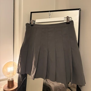 Grå kjol från Weekday - Snygg grå kjol från Weekday med veckad design. Kjolen har en dragkedja på sidan.