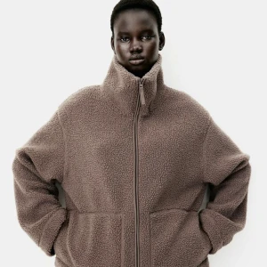 Brun teddyjacka med dragkedja - Mysig brun teddyjacka med hög krage och dragkedja framtill. Jackan har en avslappnad passform och två stora fickor. Perfekt för kyliga dagar när du vill hålla dig varm och bekväm. Använd fåtal gånger men fint skick fortfarande, känner inte att den passar mig 😊 pris går självklart att diskutera!