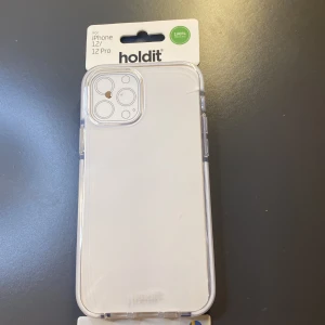 Transparent mobilskal från Holdit - Säljer ett transparent mobilskal från Holdit, designat för iPhone 12/12 Pro. Skalet är stilrent och skyddar din telefon utan att dölja dess design. Perfekt för dig som vill ha ett diskret men effektivt skydd. Genomskinlig bakom och vitt på kanterna