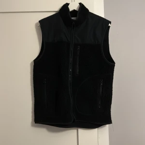 Svart fleeceväst med dragkedja - Snygg svart fleeceväst med dragkedja framtill och två praktiska fickor med dragkedjor. Perfekt för lager-på-lager under kyliga dagar. Ett bra skick på västen! Skick 9/10. Hör av er vid intresse! 