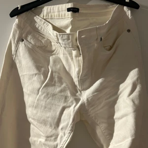 Vita jeans från Lindex i vintage  - Säljer ett par vita vintage jeans från Lindex i bra skick. De har en klassisk design med dragkedja och knappar framtill. Perfekta för både vardag och fest! 🕺