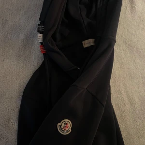 Mörkblå moncler hoodie - Mörkblå moncler hoodie, skick 8/10. Storlek M. Det är lite krångel men dragkedjan och dragkedjan är utbytt därför priset. Tveka inte att höra av dig vid minsta fundering🔥priset kan diskuteras vid snabb affär!