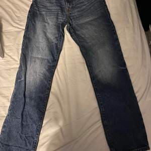 Säljer ett par klassiska blå jeans från H&M i straight regular fit. De är i bra skick och perfekta för vardagsbruk. Jag har använt dem 1 gång. Jeansen är tillverkade i ett slitstarkt material. Passar perfekt till både t-shirt och skjorta!