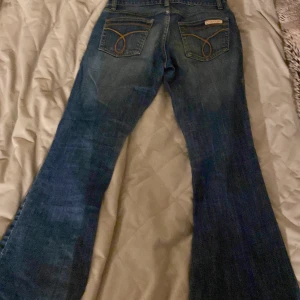 Lågmidjade bootcut jeans - Lågmidjade utsvängda jeans ifrån Calvin Klein 💓💓Super Snygga detaljer på fickorna!! Säljer då de är för små för mig och därav finns tyvärr inga bilder av de på💓 Midjemått tvärs över: 35cm innerbenslängd: 66/67