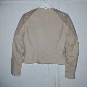 Säljer en snygg beige jacka från H&M i mycket bra skick. Jackan har quiltade detaljer på axlar och ärmar, samt en dragkedja framtill. Perfekt för höst och vår med sin stilrena design och bekväma passform. Passar både till vardags och lite finare tillfällen.