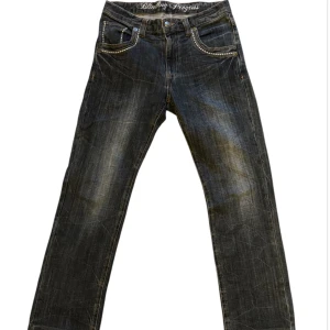 Svarta jeans med strassdetaljer - Snygga svarta jeans från Blinking Progress med coola strassdetaljer på fickorna. De har en klassisk femficksdesign och en knappgylf. Perfekta för en utekväll eller när du vill sticka ut lite extra. Passformen är normal och de är i bra skick.