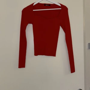 Röd ribbad topp från Gina Tricot - Snygg röd ribbad topp från Gina Tricot i ett stretchigt material. Toppen har en tight passform och långa ärmar. Den har en enkel men stilren design som gör den lätt att matcha med olika outfits. Ett måste i garderoben för den som älskar färg! 