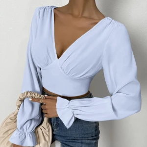 Ljusblå croppad blus med knytning - Säljer en superfin ljusblå blus med v-ringning och långa ärmar. Den är croppad och har en snygg knytning i ryggen samt dragkedja. Perfekt för vår och sommar! 💙(modellbild)