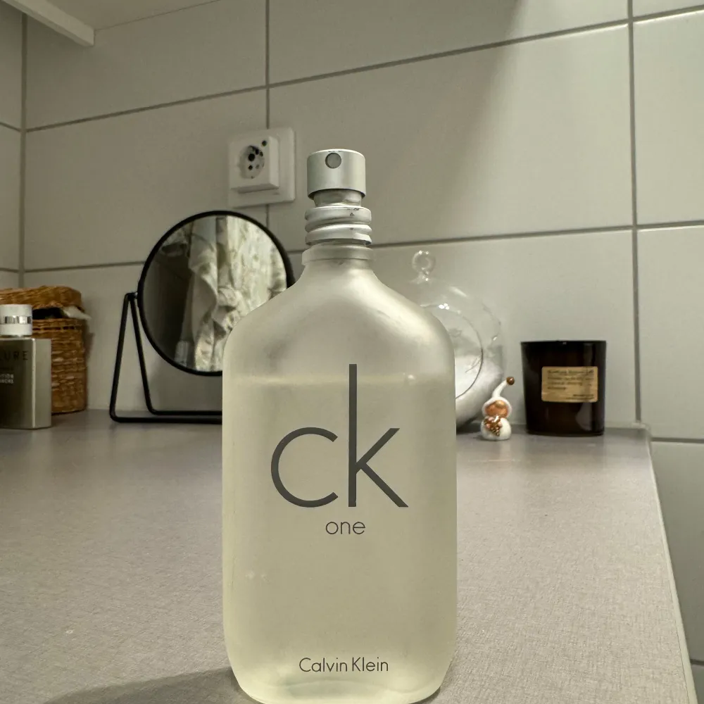 Säljer en klassisk CK One parfym från Calvin Klein. Flaskan är genomskinlig med en stilren design och grå text. Perfekt för både vardag och fest! Flaskan är stor och innehåller mycket parfym, så den räcker länge. Passar både herr och dam. Innehåller ca 43ml. Parfym.