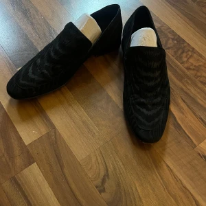 Svarta loafers från Roberto Cavalli at H&M - Snygga svarta loafers i sammet från Roberto Cavalli at H&M. De har ett subtilt mönster som ger en extra touch av stil. Perfekta för både fest och mer formella tillfällen.