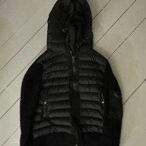 Svart dunjacka från Moncler - Säljer en snygg svart dunjacka från Moncler. Den har en quiltad design med dragkedja och huva. Perfekt för höst och vinter! Jackan är i mycket bra skick och passar både till vardags och lite finare tillfällen. 🖤