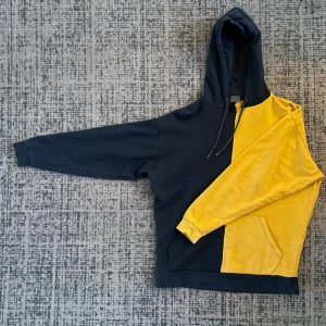 Svart och gul hoodie från CISOS - Cool hoodie i svart och gult från CISOS med texten 'PROGRESSIVE' på ryggen. Den har en klassisk känguruficka och en bekväm huva med dragsko. Perfekt för en avslappnad stil eller när du vill sticka ut lite extra. 🖤💛