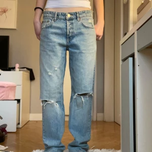 Ljusa jeans från Zara - Säljer ett par ljusa jeans från Zara i storlek 38. De har en straight passform och är snyggt slitna vid knäna. Perfekta för både vardag och fest