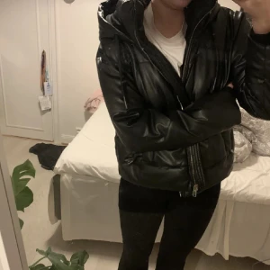 Svart pufferjacka med huva - Säljer en snygg svart pufferjacka med huva. Jackan har dragkedja och är perfekt för kyliga dagar. Den är i bra skick! 