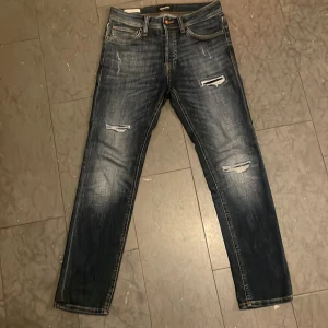 Jack & Jones jeans ”Tim” - Säljer dessa jeans från Jack & Jones i modell slim straight/tim. Jeansen är i mycket fint skick då de endast använts ett fåtal gånger. Storlek 27:30. Mörkblå färg med riktigt feta slitningar!👏