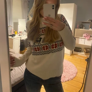 Vit stickad jultröja - Mysig cremevit stickad tröja med julmönster. Perfekt för kalla vinterdagar och julmys. Tröjan har långa ärmar och ribbade kanter. Passar både till vardags och festliga tillfällen. 