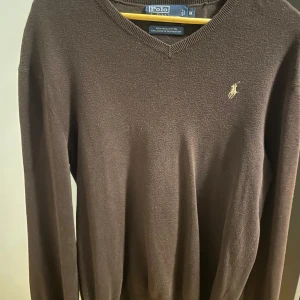 Brun tröja från Polo Ralph Lauren - Säljer en snygg brun tröja från Polo Ralph Lauren i storlek M / S. Använd ett par gånger men fortfarande i bra skick! Den är gjord av 100% Pima bomull och har en klassisk v-ringad design med det ikoniska logotypbroderiet på bröstet. Perfekt för både höst och vinter, och passar till många olika stilar. Dm för frågor och pris kan diskuteras!