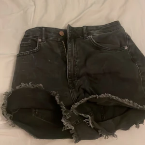 Svarta jeansshorts med fransar - Säljer ett par svarta jeansshorts i bra skick. De har en cool fransig kant. Fläcken på fickan går bort
