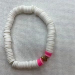 Vitt och rosa armband med stjärndetalj - Snyggt armband med vita och rosa pärlor, perfekt för att liva upp vilken outfit som helst. Armbandet har en liten guldfärgad stjärna som ger det en extra touch. Det är elastiskt och passar de flesta handleder. Perfekt för sommarens alla fester och tillfällen! 🌟