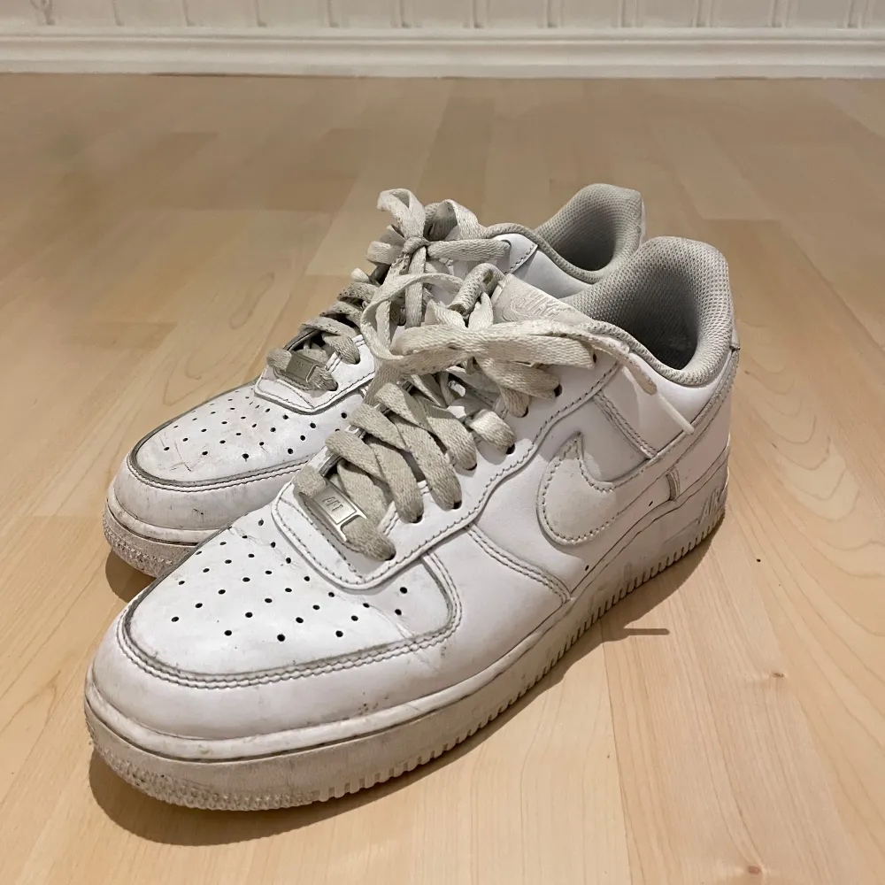 Säljer ett par klassiska vita Nike Air Force sneakers i bra skick. De har en stilren design med snörning och är perfekta för vardagsbruk. Skorna är lite slitna men fortfarande snygga och bekväma. Perfekta för både vår och sommar!. Skor.