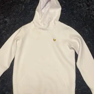 Säljer en snygg vit Lyle & Scott hoodie bra skick. Använd en gång. Den har en klassisk design med en liten gul logga på bröstet och en praktisk ficka på magen. Den har en knapp synbar defekt på bröstet som borde gå bort i tvätt (se på sista bilden). Passar ungdomar i åldern 14-15 år. Ligger på 250 kr men priset kan sänkas.