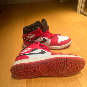 Basket skor sneakers i rött och vitt - Säljer ett par klassiska  basket skor i rött, vitt och svart. Skorna har en hög modell med snörning och den ikoniska Air-loggan på sidan. Perfekta för både vardag och fest! De är i bra skick med lite slitage på sulan och plast änden av ett av snörena är trasigt.