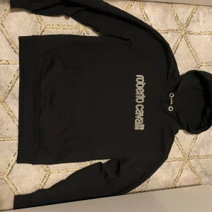 Svart hoodie från Roberto Cavalli - Snygg svart hoodie från Roberto Cavalli med logotyp i silver på bröstet. Perfekt för en stilren och bekväm look. Hoodien har långa ärmar och en klassisk huva med dragsko.